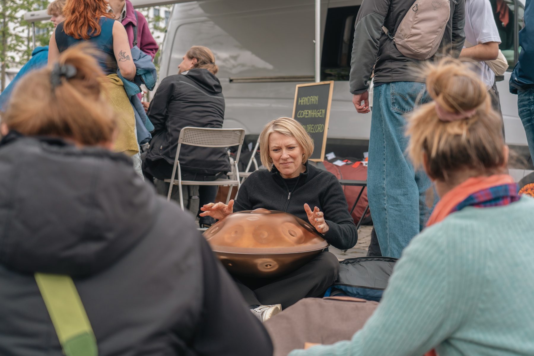 A close-up of hands playing a handpan during a community gathering
